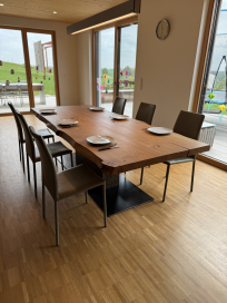 Esstisch aus Massivholz – mit natürlicher Baumkante - Esstisch aus massiver Eiche mit natürlicher Baumkante, schwarzem Metallgestell und sechs Stühlen in modernem Esszimmer